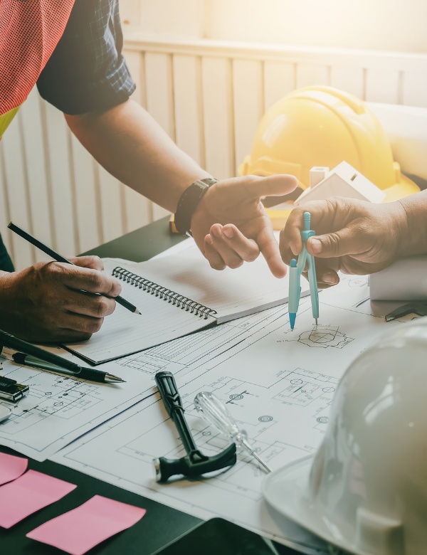 Ingénieurs et artisans travaillant sur des plans de construction pour un projet de menuiserie de précision et bardage extérieur Ingénieurs et artisans travaillant sur des plans de construction pour un projet de menuiserie de précision et bardage extérieur