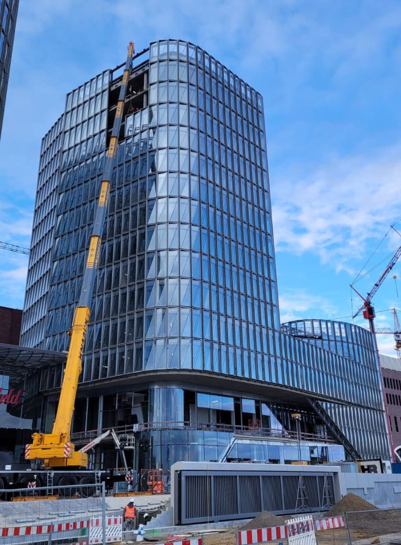 Installation de façade vitrée sur un immeuble en construction, illustrant le montage vitrage avec des panneaux de verre et des structures en aluminium Installation de façade vitrée sur un immeuble en construction, illustrant le montage vitrage avec des panneaux de verre et des structures en aluminium